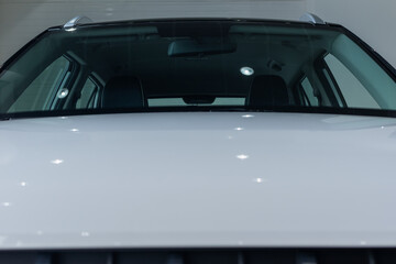 White front hood of modern car against background of windshield close-up