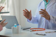 © Chadaporn - male medical practitioner reassuring a patient, Doctor and patient in conversation, Asian male doctor consulting patient, Professional physician wearing white coat talking to mature woman