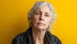 © Hannes - Thoughtful Elderly Woman with Gray Hair Against a Bright Yellow Background