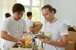 © DragonImages - Volunteers packing boxes with food for people in need and filling form on tablet