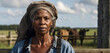 portrait of an old african farmer woman in overalls standing and leaning on a wooden fence outdoors in the countryside with a place to copy