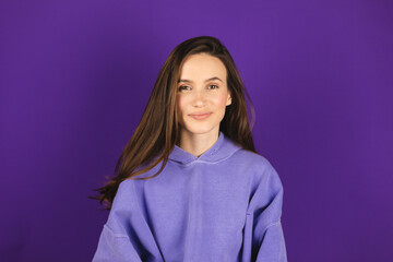 Wall Mural - Happy cheerful young woman wearing purple hoody rejoicing at positive news or birthday gift, looking at camera with joyful and charming smile. Brunette girl very glad smiling with broad smile.