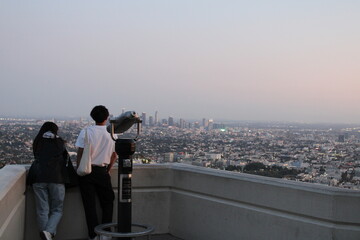 Los Angeles, California, USA; October 24 2023: Young couple watching Los Angeles skyline from the Griffith Park observatory.