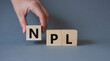 © Natallia - NPL - Non Performing Loan symbol. Concept word IPO on wooden cubes. Businessman hand. Beautiful grey background. Business and NPL concept. Copy space.