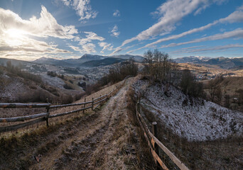 Winter coming. Last good weather days in autumn mountain countryside morning picturesque scene. Dirty road from hills to the village. Hoverla and Petros Ukrainian Carpathians mountains in far.