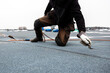 professional roofer applying bitumen roll on flat roof with a gas burner at a modern construction site