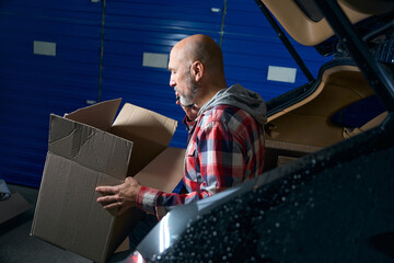 Bald guy carries a cardboard box with things