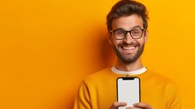 Portrait Image Of Happy Smiling Casual Man In Eye Glasses Hold Peep Out Stand Behind Big Cell Phone, Smartphone, Isolated On Orange Yellow Background. Mockup Empty Blank White Cellphone Screen