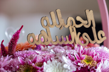 Pink Bouquet with heart shape and multi colors and balloons in the background as decoration for celebrationwith arabic word translation : الحمدلله على السلامة (Thank god for safty)