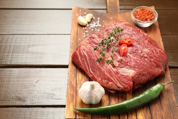 Fresh raw beef cut with spices on wooden table. Space for text