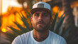 © Jammy Jean - Young man wearing a trucker hat and white t shirt outside.