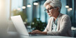 © ImageFlow - A senior woman CEO working on laptop in modern office with natural light. Corporate success concept. Generative AI