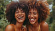 Two brown identical twin sisters laughing together.