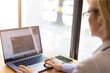 © Александра Алероева - A young woman works on a laptop in an office, a student studies in class. Woman in glasses entering data into laptop and taking notes, business, freelancing, concept of working in office, girl with