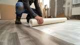 Fototapeta  - A person in work boots rolling out a large sheet of vinyl flooring in a bedroom carefully smoothing out any air bubbles.