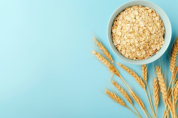 Top view of a bowl with plain oats and wheat on light blue background representing the concept of cooking oats porridge Free space available for text on banner