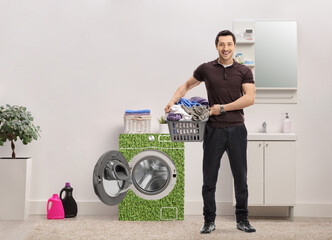 Poster - Man with a laundry basket full of clothes standing in a bathroom next to energy efficient waching machine