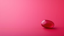 A Glossy Red Jelly Bean On A Pink Surface