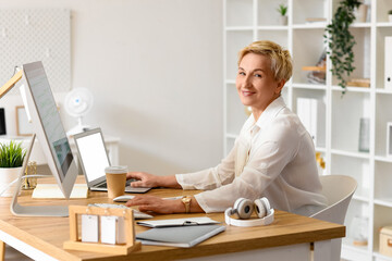Mature female programmer working at table in office
