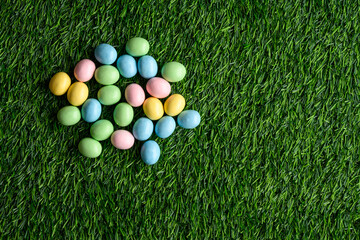 Wall Mural - Happy Easter, pastel colored candy coated Easter eggs on artificial green grass
