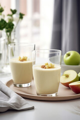 Wall Mural - Apple smoothie in two glasses in white modern kitchen with green apples, healthy breakfast or snack idea