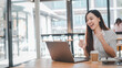 © Satori Studio - Business analytics concept, A joyous businesswoman celebrates a successful moment while working on her laptop at a bright office table with a takeaway coffee cup.
