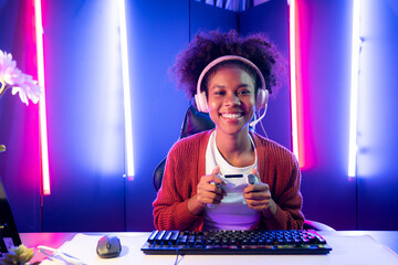 African American girl gaming streamer team winner playing online fighting with Esport wearing headphones in neon lighting room. Talking other players planing strategies to win competitors. Tastemaker.