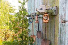 The Gardening Tools Hanging On Old Wooden Wall Vintage.