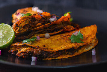 3 Beef Birria Tacos Stacked on Black Plate