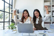 © Phimwilai - Two Asian businesswomen rejoicing over success in business, smiling and expressing joy. success in starting an online business partner teamwork concept.