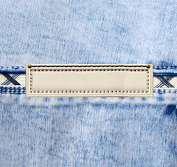 Sticker - Blue denim texture with a seam and old leather label. Light blue color denim jeans material and vintage tag of ivory color. Mock up template. Copy space for text