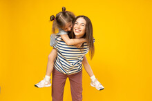 Mother And Daughter Are Playing, On A Yellow Background.