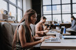 © Halfpoint - Beautiful businesswoman working on laptop in modern office. Group of freelancers working in shared work area. Concept of coworking, common workspaces for business, startups.