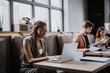 © Halfpoint - Beautiful businesswoman working on laptop in modern office. Group of freelancers working in shared work area. Concept of coworking, common workspaces for business, startups.