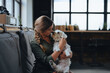 © Halfpoint - Portrait of beautiful young woman holding her dog in hands. Cute white dog in arms of loving owner. With dog in coffe shop.