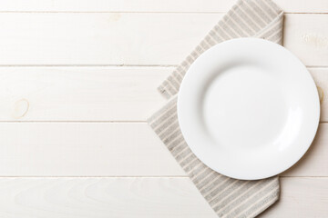 Wall Mural - Top view on colored background empty round white plate on tablecloth for food. Empty dish on napkin with space for your design