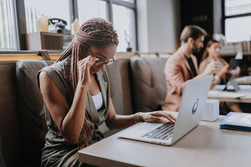 Wall Mural - Beautiful businesswoman working on laptop in modern office. Group of freelancers working in shared work area. Concept of coworking, common workspaces for business, startups.