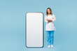 © ViDi Studio - Full body doctor woman wears white medical gown suit work in hospital clinic office stand near big huge blank screen mobile cell phone isolated on plain blue background. Health care medicine concept.