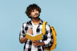 © ViDi Studio - Young Indian boy student he wear shirt casual clothes backpack bag hold books write down in notebook look aside isolated on plain pastel light blue background. High school university college concept.