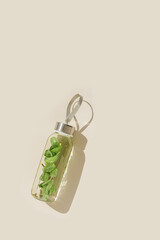 Wall Mural - Water drink detox with green mint leaves in glass bottle at sunlight on beige background. Wellness, diet, eating healthy concept. Stylish glass reusable water bottle, lifestyle minimal trend