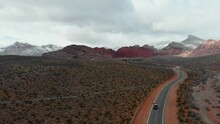 Aerial Drone Shot Along A Small Road With Snow Flurries And Mountains In The Background. Cinematic Shot Of Calico Basin In Nevada's Mojave Desert, USA. 4K UHD. Scenic, Nature, Landscape, Travel.
