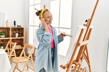 Wall Mural - Young caucasian woman artist listening to music drawing at art studio