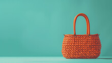 A Vibrant Orange Woven Handbag On A Cool Turquoise Background, Showcasing Its Unique Texture With Room For Copy. 4K, Epic Details.
