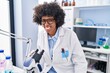 African american woman scientist smiling confident using microscope at laboratory