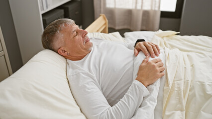 Canvas Print - Middle-aged man relaxing in a cozy bedroom, conveying a sense of tranquility and comfort.