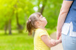 © Ermolaev Alexandr - Little girl with syndrome down holds mother's hand at sunny summer park