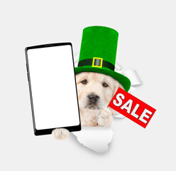 Aufkleber - Saint Patrick's Day concept. Golden retriever puppy wearing green leprechauns top hat holding big smartphone with white blank screen and showing signboard with labeled 