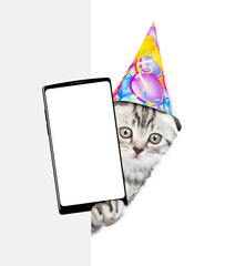 Wall Mural - Cute kitten wearing party cap shows big smartphone with blank screen from behind white banner. isolated on white background