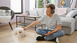 Engrossed young caucasian man sitting on the floor at home, deeply focused on a song playing on his smartphone using headphones while his adult dog patiently waits beside him