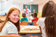 © Robert Kneschke - Smiling girl sitting with classmate in school